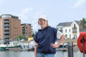 Yachts and a teenage girl on an embankment.  Baseball cap blue sweater. copy space