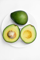 Sliced green avocado on a white background. Pieces of green vegetable on a white plate. Delicious food for a vegan.