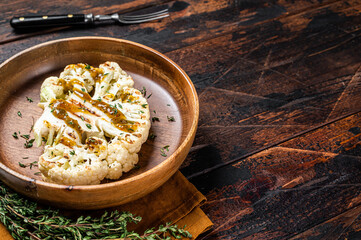 Grilled Cauliflower steaks with a cilantro lime chimichurri sauce, Plant based meat substitute concept. Wooden background. Top view. Copy space