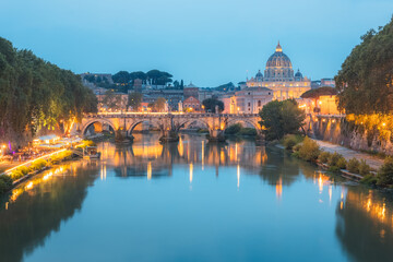 Sceninc twilight view of Saint Peter's Basilica at Vatican City and Ponte Vittorio Emanuele II illuminated along the Tiber River on a summer evening in Rome, Italy. - obrazy, fototapety, plakaty
