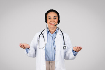 Telemedicine, e-health. Happy brazilian woman doctor with headset and stethoscope, gesturing and smiling at camera