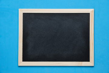 Black blackboard for notes in wooden frame blue background.