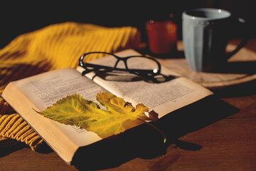 Autumn. cup of tea, maple leaves, sweater and books on wooden table. cozy home, hygge concept