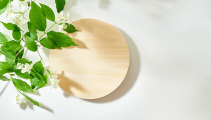 Flat lay wooden round podium on a white background with sunlight and shadows of jasmine leaf flowers