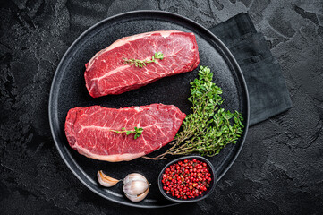 Dry aged Raw top blade flat Iron beef meat steaks. Black background. Top View