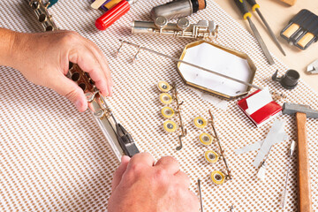 repairing a flute in the foreground. two hands removing a shaft with pliers. © Boscaeta