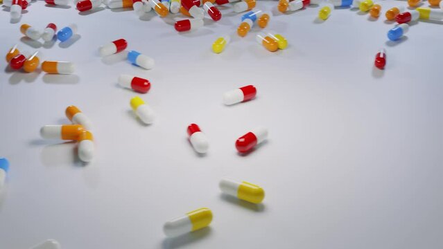 Many colorful capsule pills fall down from two sides. View from the top 3D render video.