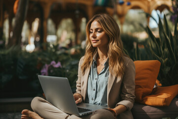 A woman sitting on a bench using a laptop. Bleisure or workation, person working remotely.