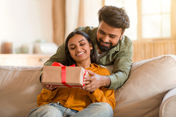 Loving indian husband giving present gift box to wife, man celebrating birthday with his beloved...