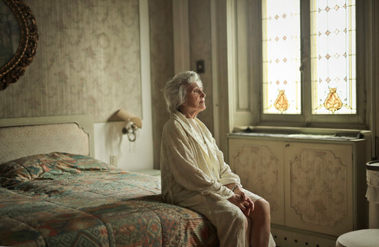 elderly lady in dressing gown on bed