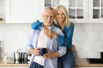 Fototapeta na wymiar Portrait of romantic attractive senior couple standing at cozy kitchen interior