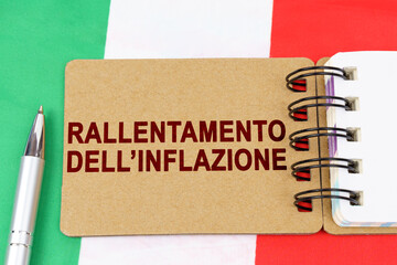 On the flag of Italy lies a pen and a notebook with the inscription - inflation slowdown