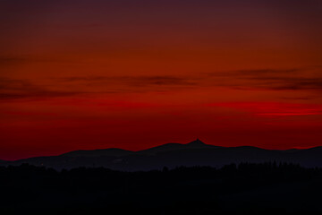 Dark silhouette of leaf trees after cloudy red sunset in Krkonose mountains