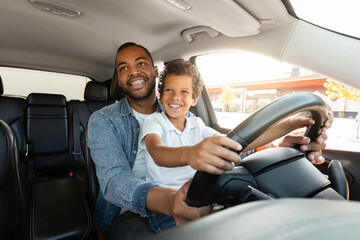 Happy african american father and son driving car together - obrazy, fototapety, plakaty