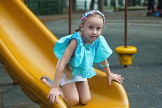 Energetic schoolgirl in casual attire gleefully slides through a maze on the playground in the park, embracing her playful spirit.  - Powered by Adobe