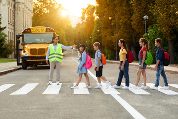 Road Traffic Safety. School Bus Assistant Helping Kids Cross Road By Crosswalk