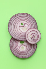 Slices of fresh red onion on green background
