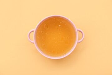 Pot of tasty vegetable broth on orange background
