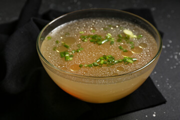 Bowl of tasty vegetable broth on black background
