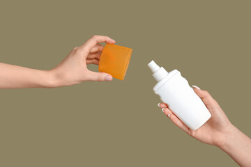 Female hands with bottles of sunscreen cream on green background
