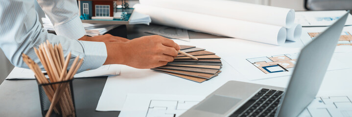 Interior architect designer at workstation table designing house interior blueprint and choosing...