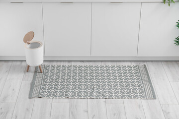 Stylish rug and trash bin on floor in kitchen