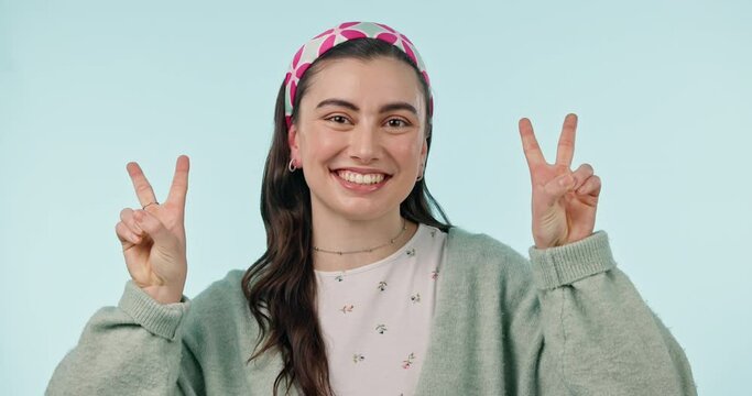 Face, happy woman and sign of peace in studio of winning, vote or celebrate success on blue background. Portrait, young gen z model and hands show v icon, symbol or emoji of freedom, support or pride