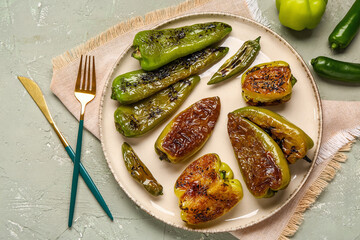 Plate with different grilled peppers on grey background