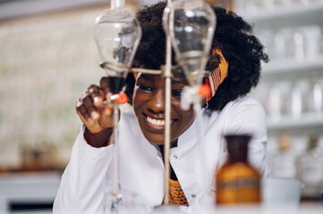 A cheerful african american female apothecary technician is working on a cure.