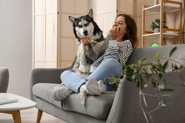 Happy young woman with husky dog at home
