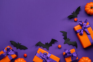 Composition with gift boxes, pumpkins and paper bats for Halloween on purple background