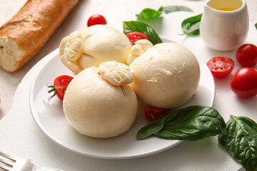 Plate of tasty Burrata cheese with basil and tomatoes on white background