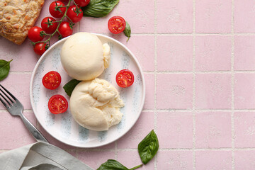 Plate of tasty Burrata cheese with basil and tomatoes on pink tile background