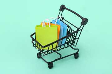Small shopping cart with bags on turquoise background