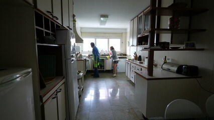 Senior couple standing at kitchen at home, genuine family lifestyle scene of elderly man and woman cooking meal preparation