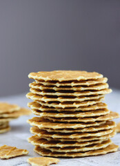 Stack of butter waffle cookies on a grey background with copy space, selective focus. Waffle crisps close-up. Tasty home made thin waffles, vertical image