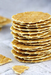 Close-up of a stack of butter waffle cookies on a grey background, selective focus vertical image. Waffle crisps close-up. Tasty home made thin waffles