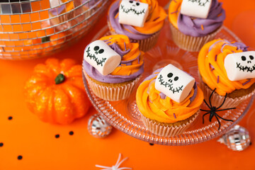 Halloween cupcakes decorated with spooky marshmallows on orange table, closeup