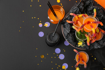 Halloween party composition with punch and gummy worms on black table