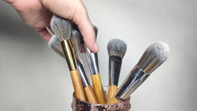 woman putting one makeup brush at a time into a storage case close-up
