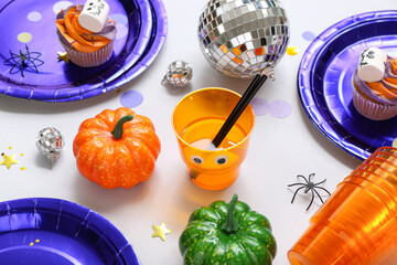 Halloween party table setting with pumpkins, punch and decor on grey background