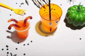 Halloween party table setting with punch and gummy worms on white background