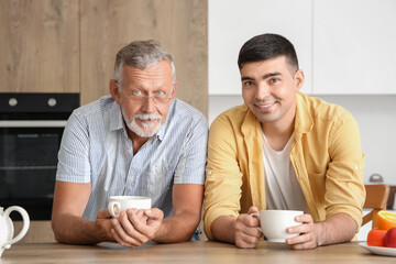 Senior man with his son drinking tea in kitchen