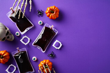 Happy Halloween holiday flat lay composition. Top view blood packets, pumpkins, skull, eyes on purple background.