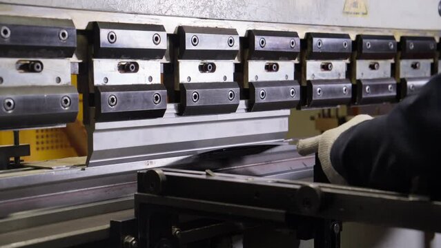 Operator places metal sheet on machine that folds it. Bending sheet metal on hydraulic machine at factory. perator bending metal sheet. 4K, UHD
