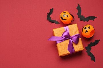 Composition with gift box and Halloween decorations on red background