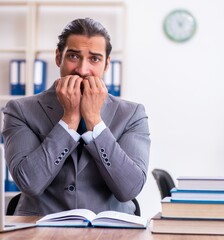 Young male businessman reading books at workplace