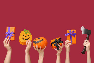 Female hands holding Halloween gifts and decor on red background