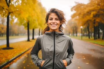 Deurstickers Happy female runner jogging on a park on an rainy autumn day © MVProductions