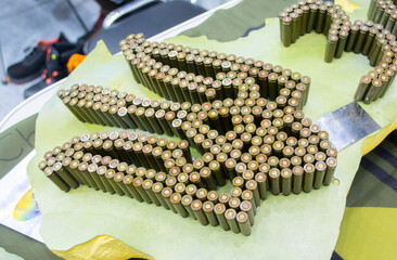 Emblem, coat of arms of Ukraine trident from used cartridges. Object made up of spent used cartridge cases. Lots used shells from cartridge cases ammo close up. Model from Many Used cartridge Cases.
